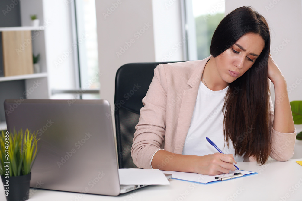 Young female content manager makes notes with a pen Young female content manager makes notes with a pen