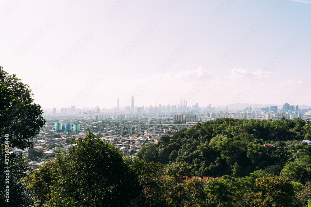 Fototapeta premium View from a hill with trees of a city with the skyscrapers in the background