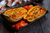 Closeup of baked pumpkin with vegetables on a metal baking sheet on a dark wooden table.