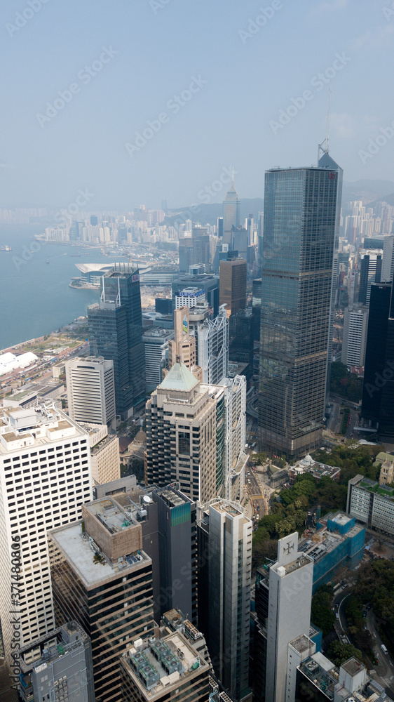 Hong Kong / March 28 2018: Aerial view of Hong Kong city. Skyscrapers, office glass buildings business centers near Victoria harbour bay concrete jungle megalopolis cityscape city life. Sunny blue sky
