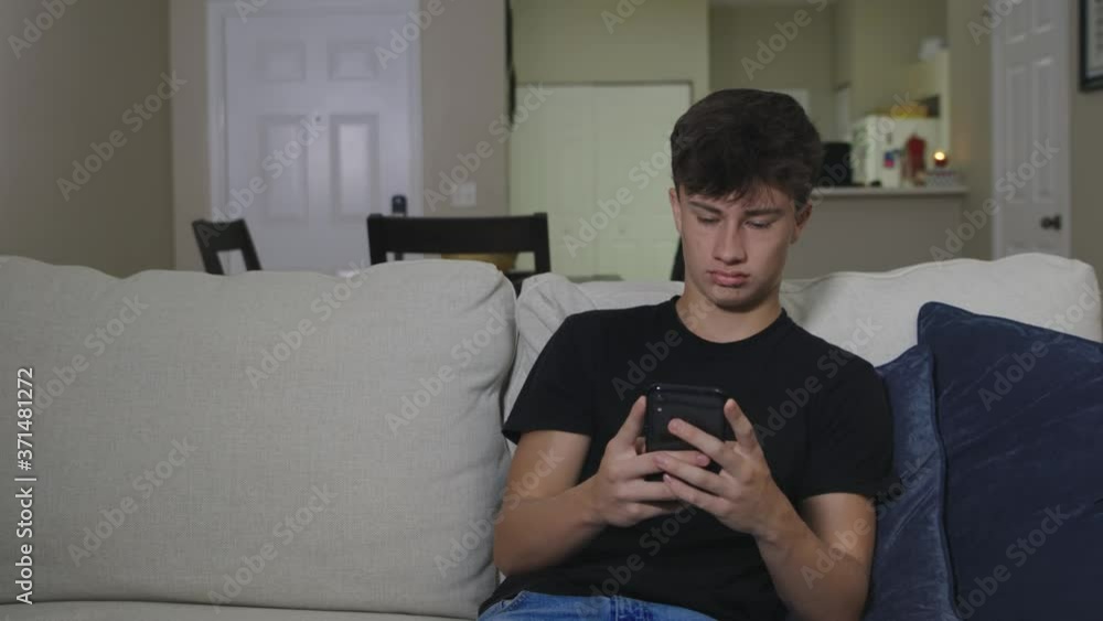 Stressed young male teenager sad texting on cell phone mobile device on couch slide down
Stressed young male teenager sad texting on cell phone mobile device on couch slide down