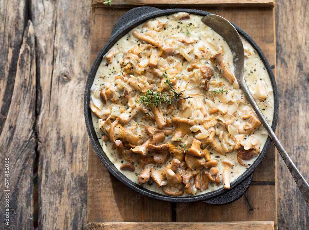 Fried chanterelle mushrooms with onions or stew on wooden background. Selective focus. Fried chanterelle mushrooms with onions or stew on wooden background. Selective focus.