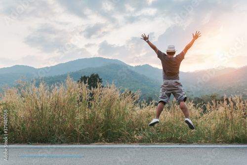 Happy young man jumping on the meadow ,Hipster traveler jumping against the mountains,copy space for text.