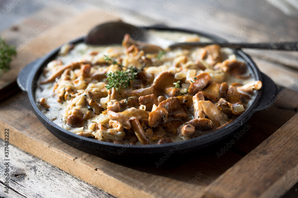 Fried chanterelle mushrooms with onions or stew on wooden background. Selective focus. Fried chanterelle mushrooms with onions or stew on wooden background. Selective focus.