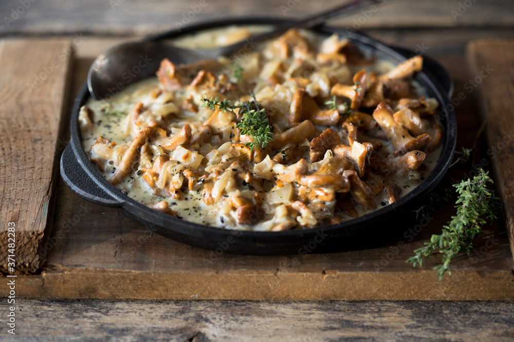 Fried chanterelle mushrooms with onions or stew on wooden background. Selective focus. Fried chanterelle mushrooms with onions or stew on wooden background. Selective focus.