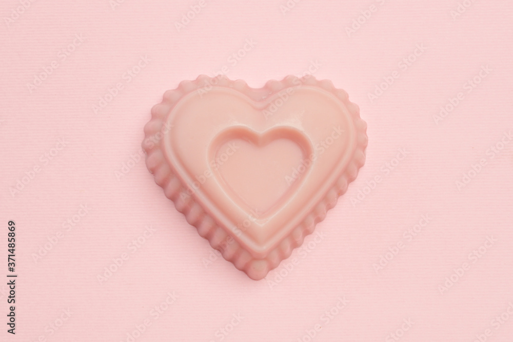 Heart-shaped pink handmade soapon pink background, close up	
