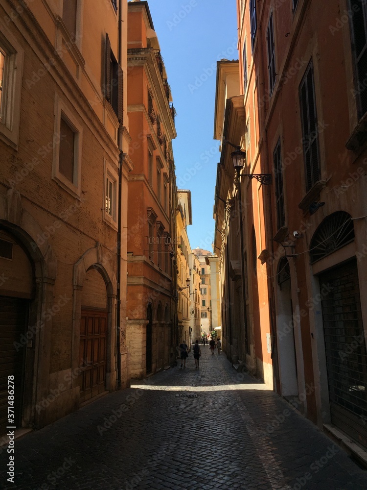 A narrow street of Rome and yellow old houses and blue sky
