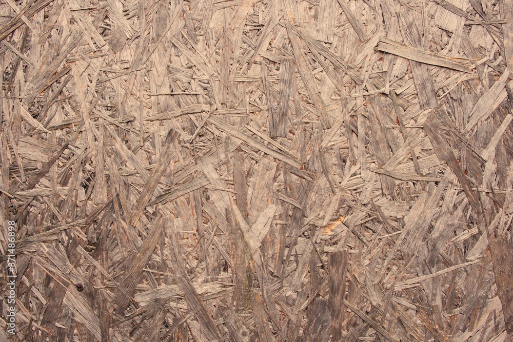 Texture of Oriented Strand Board (OSB). Versatile waterproof structural wood panel manufactured from rectangular shaped strands in cross-oriented layers that resists deflection, delamination, warping. Texture of Oriented Strand Board (OSB). Versatile waterproof structural wood panel manufactured from rectangular shaped strands in cross-oriented layers that resists deflection, delamination, warping.