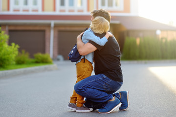 Little boy says goodbye and hugging to his father before going to school. Education for children. First day of school.