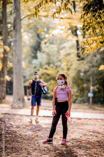 Fototapeta Naklejka Na Ścianę i Meble -  Young sporty man and girl are training in the park. They are wearing a protective face mask
