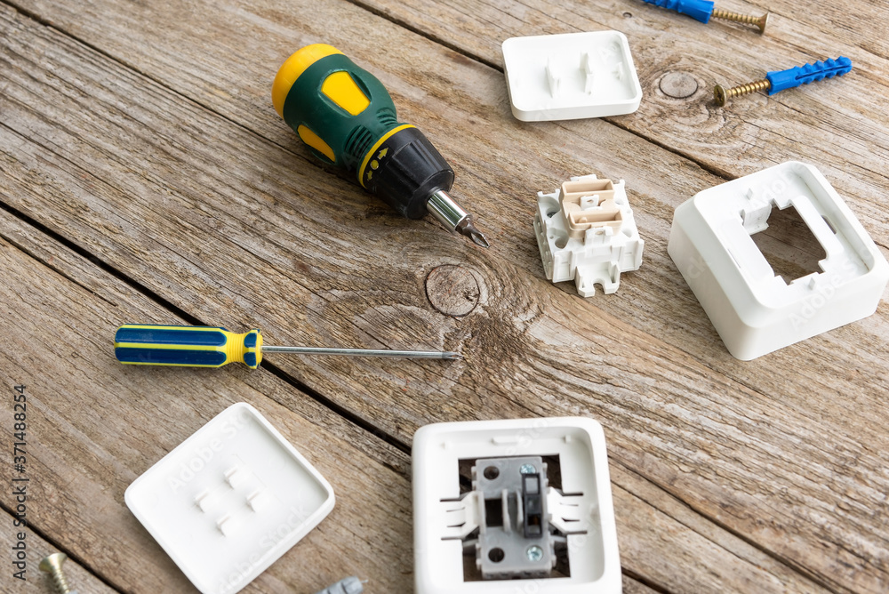 Disassembled socket and switch on the table along with a screwdriver and dowels. Disassembled socket and switch on the table along with a screwdriver and dowels.