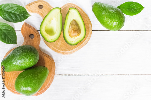 fresh avocado on a chopping Board close-up view from above. background with fresh whole avocado and avocado halves. avocado on a white background lying flat.