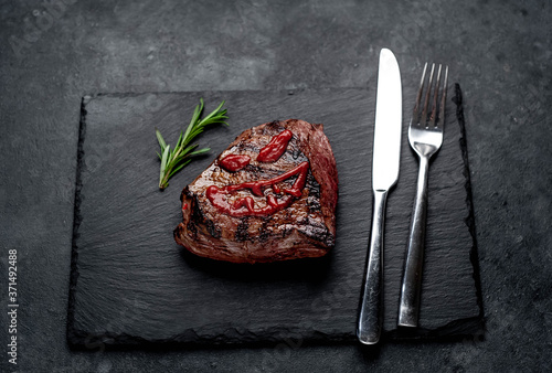 grilled beef steak with spices, knife and fork for halloween on stone background