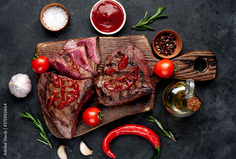 Two grilled beef monster steaks with spices for halloween on stone background