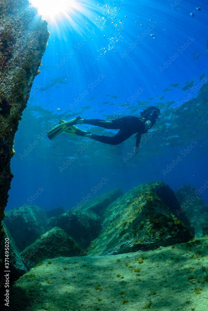 a scuba diver swims above a Mediterranean seabed a scuba diver swims above a Mediterranean seabed