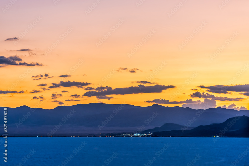 Bonneville Salt Flats colorful orange blue dark twilight silhouette mountain view with highway lights after sunset near Salt Lake City, Utah with clouds