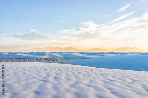 White sands dunes national park monument hills of gypsum sand in New Mexico with Organ mountains silhouette on horizon during colorful yellow sunset
