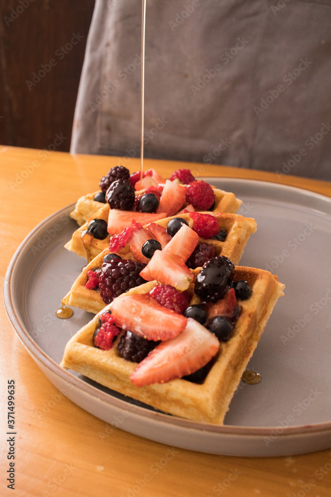 Vertiendo miel sobre waffles con frutos rojos Vertiendo miel sobre waffles con frutos rojos