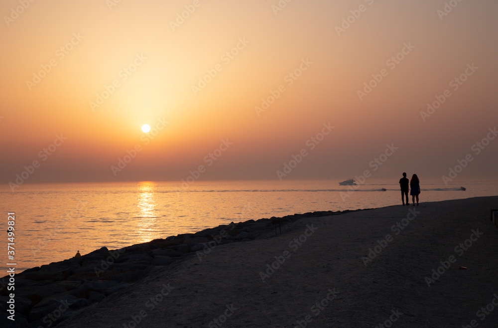 Bubai - The silhouette of pair on the coast at the sunset light,.