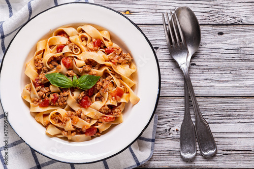 Traditional italian pasta bolognese on a white plate on a wooden background