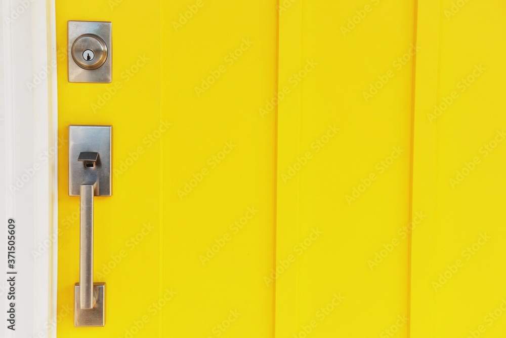 yellow door with a modern metal handle and lock yellow door with a modern metal handle and lock