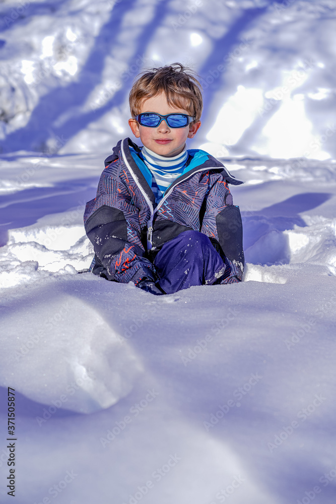 Soft focus background. Young Boy With Sunglasses Playing In The Snow. Winter sunny day on the french alps