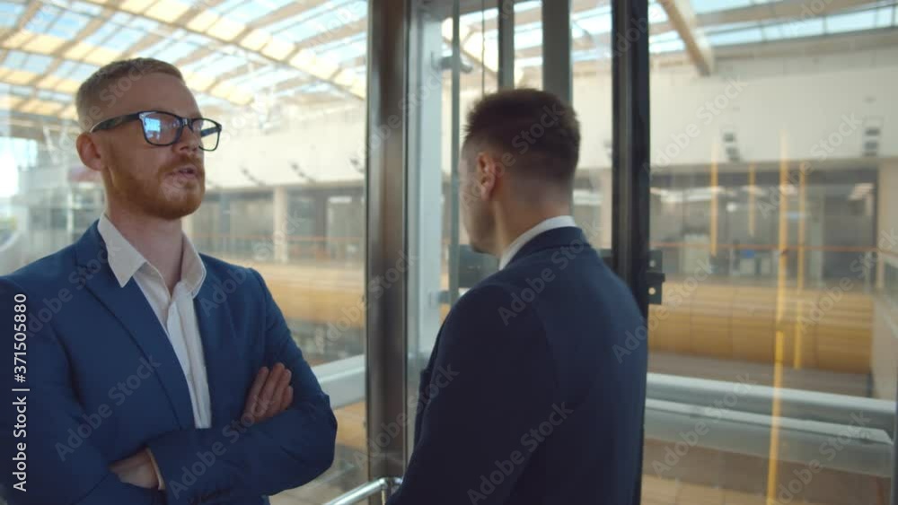 Diverse work colleagues using glass elevator in modern office building Diverse work colleagues using glass elevator in modern office building