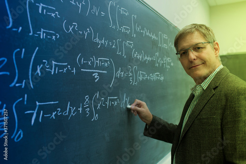 Caucasian teacher writing on chalkboard photo