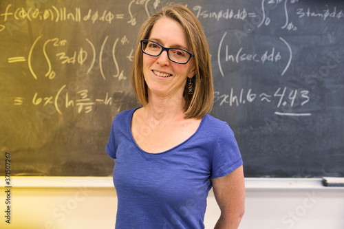 Caucasian teacher standing at chalkboard photo