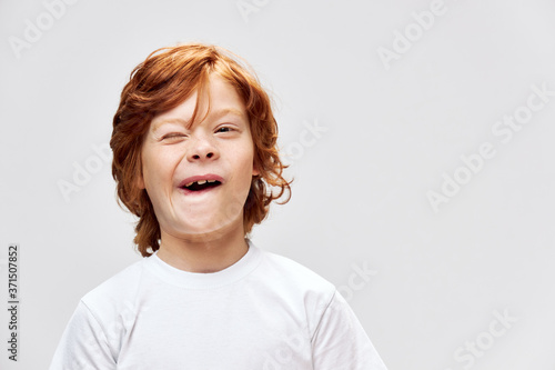 Cheerful redhead child white t-shirt smile Studio gray isolated 