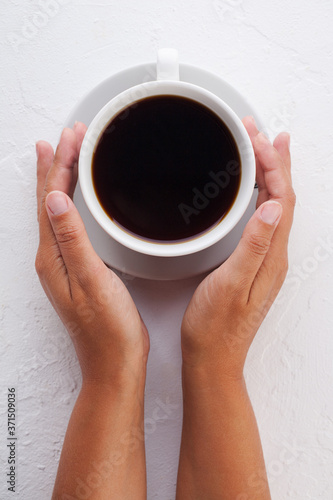 women's hands hold a white coffee mug on a white background.