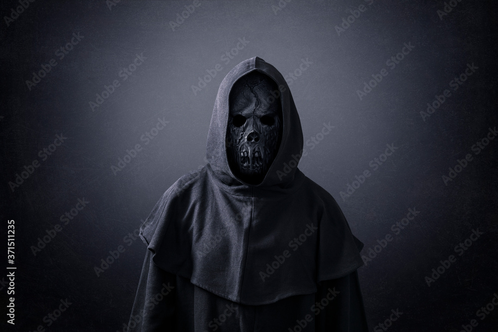 Scary figure in hooded cloak in the dark Scary figure in hooded cloak in the dark