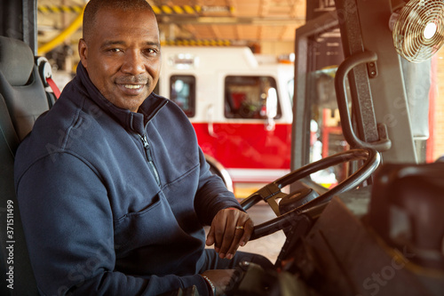Portrait of fireman sitting in driver's seat of fire engine photo