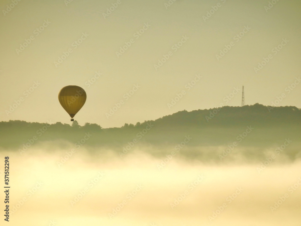 Hot air balloon floating over the Dordogne landscape at sunrise, as viewed from another balloon Hot air balloon floating over the Dordogne landscape at sunrise, as viewed from another balloon