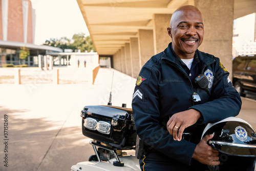 Portrait of Police officer sitting on his motorcycle outside looking towards camera smiling  photo