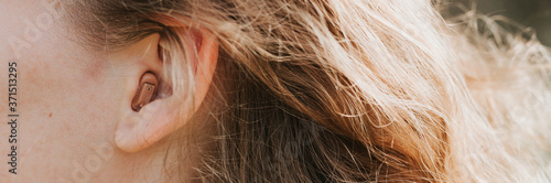 small intra channel hearing aid in the ear of a woman. banner