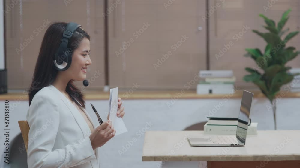 Young Indian business woman on headset using laptop communicates on internet with customer in home. Distance advice webinar online chat and teaching concept Young Indian business woman on headset using laptop communicates on internet with customer in home. Distance advice webinar online chat and teaching concept
