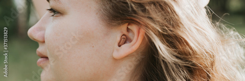 small intra channel hearing aid in the ear of a woman. banner