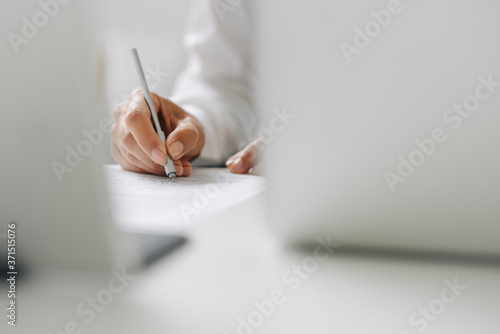 Close-up of female entrepreneur writing on paper at desk in home office photo