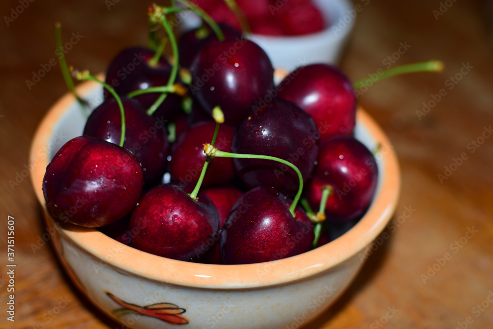 Sweet cherries in a ceramic bowl on a wooden table. Close-up Sweet cherries in a ceramic bowl on a wooden table. Close-up