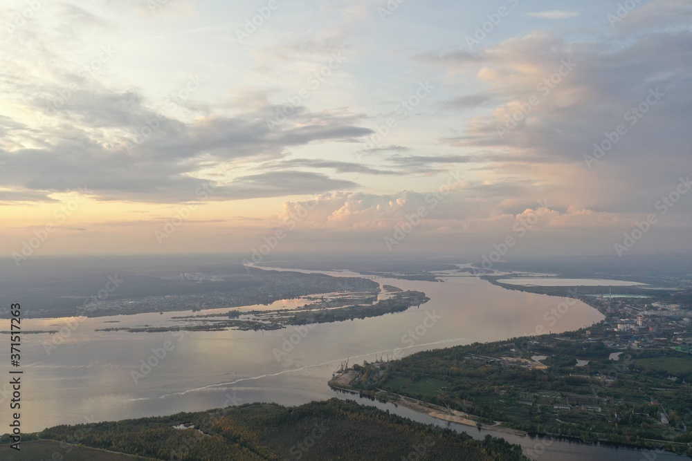Fototapeta premium View from the drone to the river, bridge, factories in the evening. Cumulus clouds.