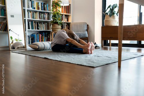 Young woman exercising while sitting on rug at home