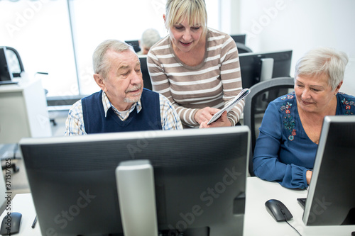 Active seniors attending computer course, intructor giving advice photo