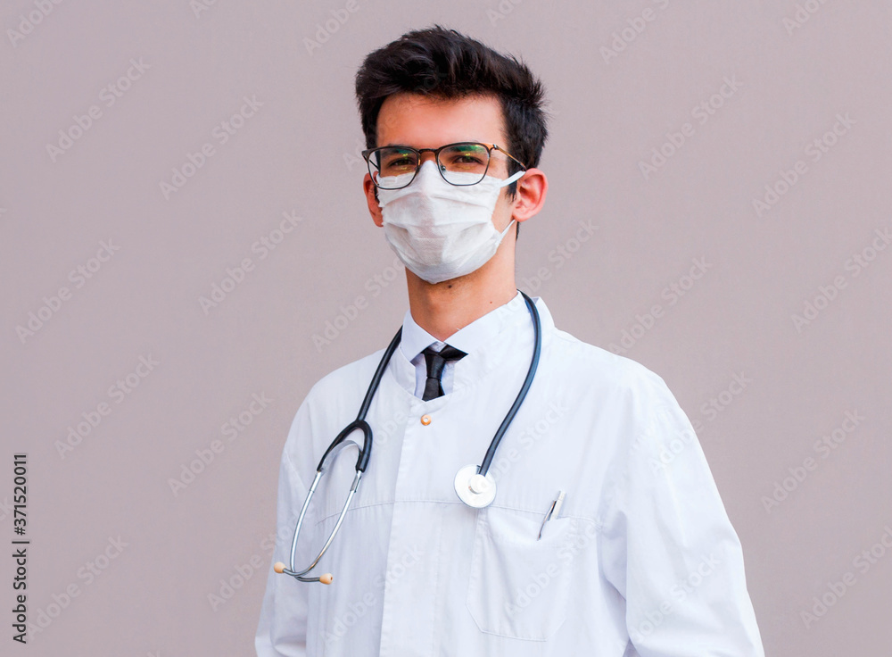 Potrait of handsome doctor wearing surgical protective mask isolated on gray background Potrait of handsome doctor wearing surgical protective mask isolated on gray background