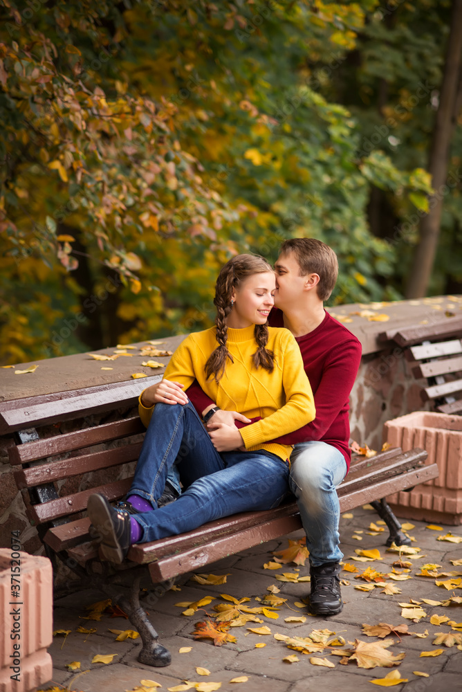 happy young couple sitting on a bench in the autumn Park