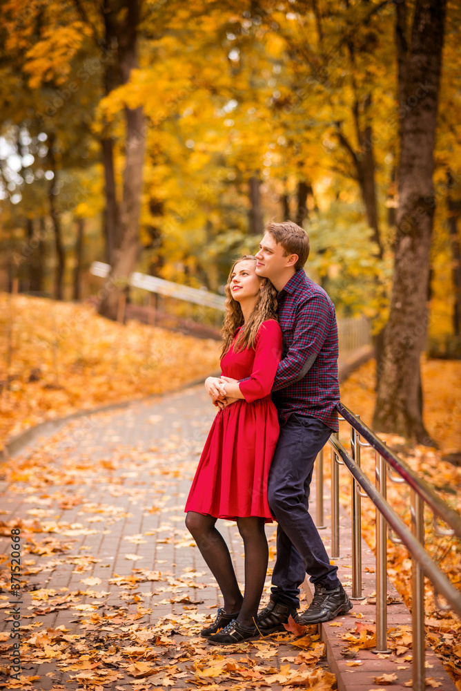 young couple walks in the autumn Park. Orange and yellow leaves around young couple walks in the autumn Park. Orange and yellow leaves around