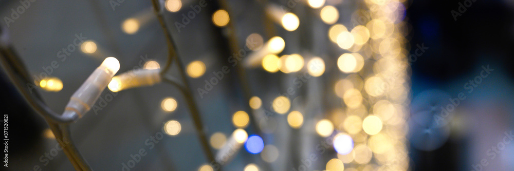 blurred glowing lights of garlands of golden color, bokeh. banner