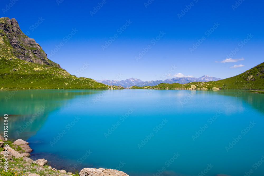 Alpine mountain lake at the daytime, sunlight and colorful landscape