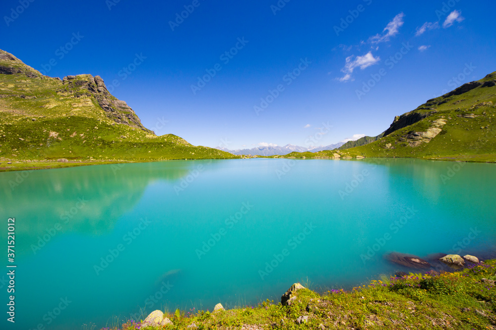 Alpine mountain lake at the daytime, sunlight and colorful landscape