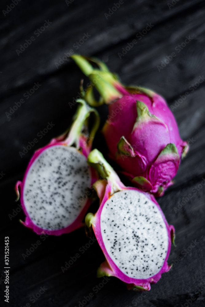 Close up view of exotic dragon fruit sliced isolated on a wooden background. Fresh vegetarians vitamin delicious food. Beautiful picture of summer vacation fruits Close up view of exotic dragon fruit sliced isolated on a wooden background. Fresh vegetarians vitamin delicious food. Beautiful picture of summer vacation fruits